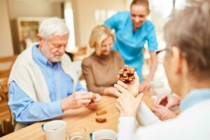 The Gardens of Castle Hill | Caregiver cares for seniors in retirement home in dementia therapy with wooden puzzle