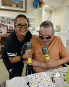 The Gardens at Castle Hills | Alma and senior resident, Henry, holding fake microphones and smiling